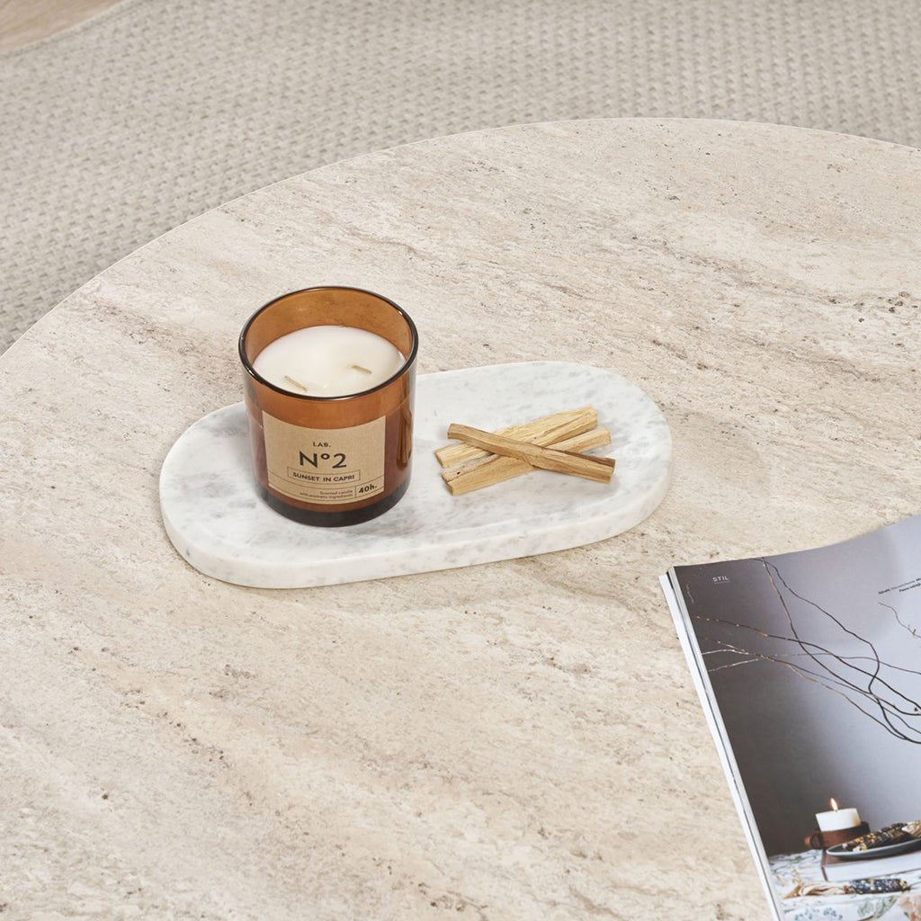 Mesa de centro redonda con tapa de travertino y base de madera oscura en forma de cruz.